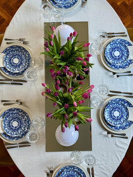 Overhead view of a formal dinner party table setting for six people with fresh tulip centrepieces