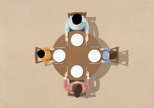 View from above of family sitting at table with empty plates, waiting for food