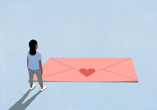 Woman looking at large pink envelope with heart sticker on blue background