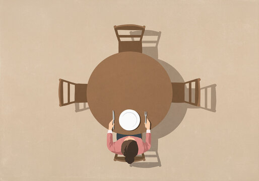 View from above of woman sitting at table with empty plate