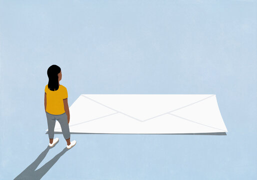 Woman looking down at large white envelope on blue background