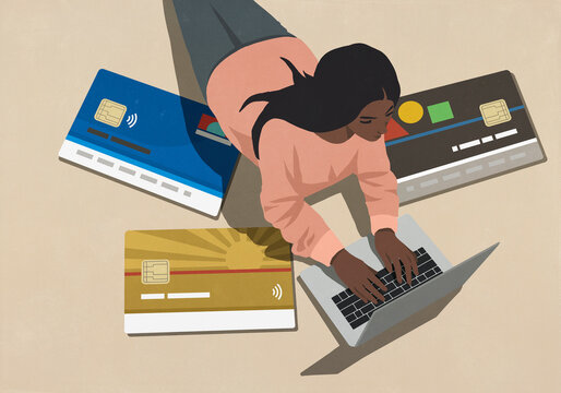 High angle view large credit cards surrounding young woman using laptop