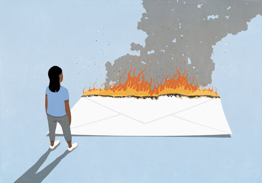 Woman watching large envelope burning against blue background