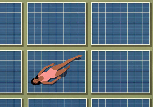 View from above of woman in bathing suit sunbathing on top of solar panels