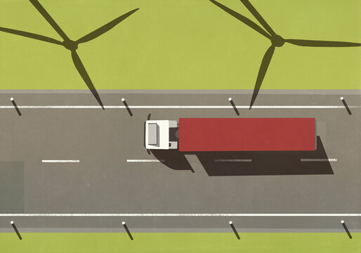 View from above of semi truck driving on road past shadows of wind turbines in sunny rural field