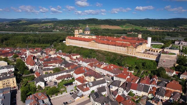 Melk Abbey Austria Aerial 4K. Drone cinematic panoramic view of Benedictine abbey and historic town. Scenic Danube river landscape behind yellow baroque monastery. Sunny summer travel destination