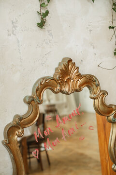 Close-up of lipstick kisses and the words Mon Amour Mon Ami written on a mirror with lipstick