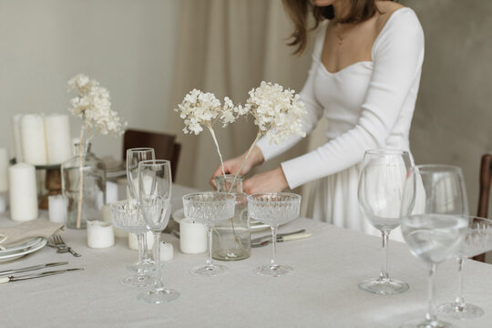 Close-up of a woman standing at a dining table setting the table for a dinner party