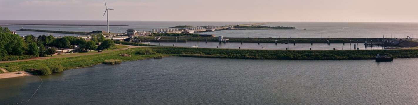 Aerial view of the Stevinsluis sluice complex with a wind turbine and water channels in Den Oever, Noord-Holland, Netherlands.