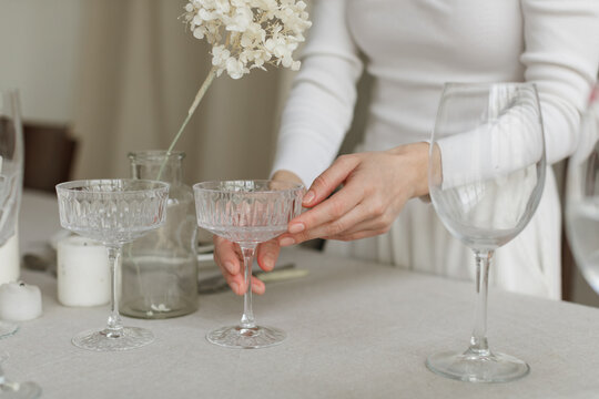 Close-up of a woman standing at a dining table setting the table for a dinner party