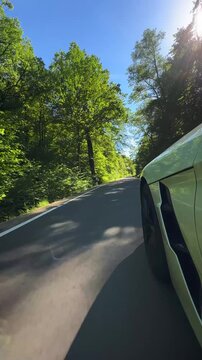 convertible car in sunny nature on a bright summer day. wide angle pursuit shot - vertical video for reels and story
