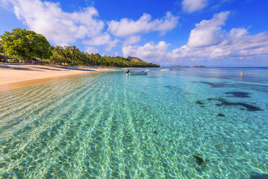 Dravuni Island, Fiji. Beach, boat and palm trees in the South Pacific ocean.