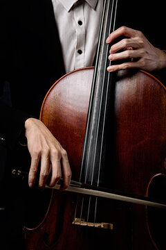 Close-up of a male cellist in a suit playing a cello