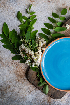 Close-up overhead view of a ceramic plate on a wooden chopping board with fresh acacia flowers