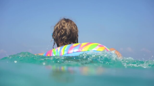 A happy child is having fun in the sea during the summer holidays. Slow motion
