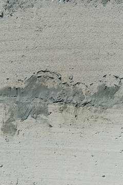 Close-up rough stucco surface with dark grey cement patching and visible flaws. Architectural texture background for construction, renovation, and material analysis concepts