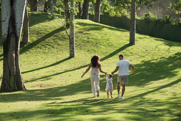 Fototapeta premium Family walking away together across tropical green landscape.