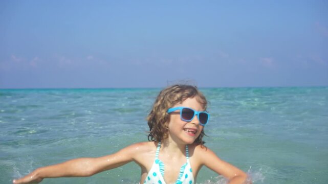 A happy child is having fun in the sea during the summer holidays. Slow motion