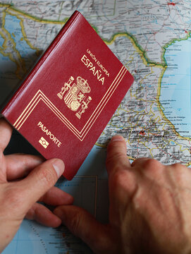 Viaje con pasaporte Espa&ntilde;a y mapa con documento para viaje y visado passport visa con trayecto ruta viajar pa&iacute;s extranjero y dedo indicando destino viajero lugar vacaciones de verano