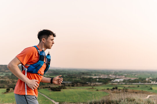 Athlete wearing hydration vest running on a rural hill