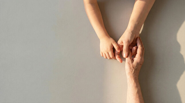 Hands holding, adult and child connection, gentle touch warm light, care love.