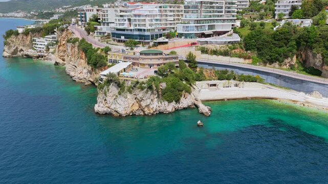 Aerial view of Vlora's  clifftop developments, winding coastal road and turquoise Ionian sea