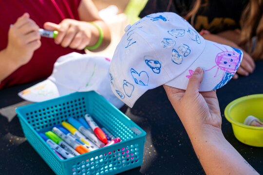 Crafts and children's activities. Children decorating caps with colored fabric markers