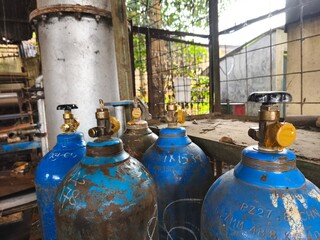 Obraz premium Industrial Gas Cylinders in Workshop Area with Rusty Metal Texture