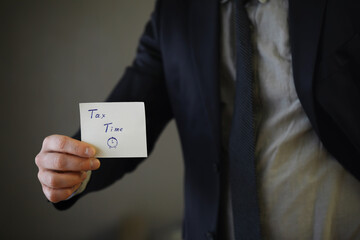 Naklejka premium Businessman in a suit hand holding sticker with tax time