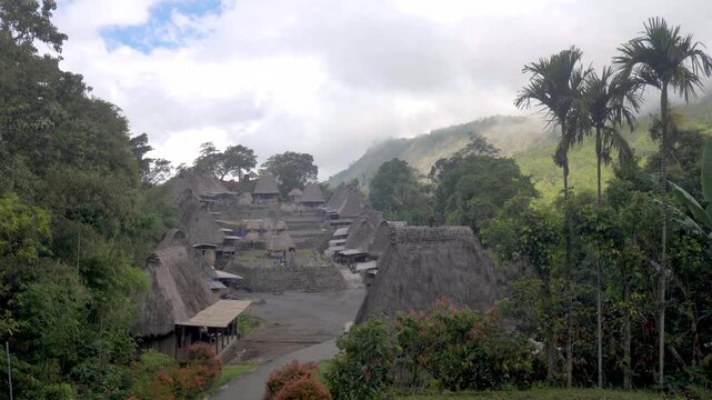 Traditional Bena village near Bajawa on Flores Island, Indonesia, surrounded by lush tropical forest and misty hills, featuring authentic thatched houses and indigenous architecture