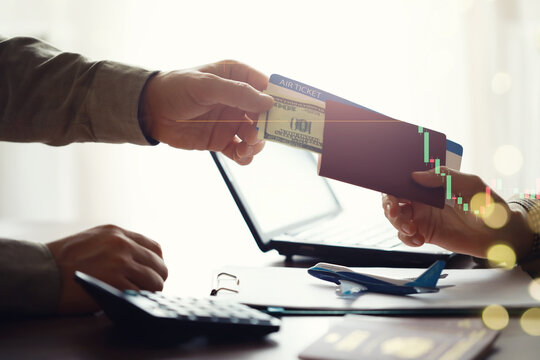 A man buys plane tickets from an agency. The client receives a passport with plane tickets from the travel agent.