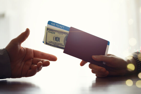A man buys plane tickets from an agency. The client receives a passport with plane tickets from the travel agent.