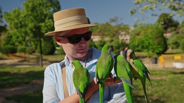 Woman feeding monk parakeets in Ciutadella Park near Arc de Triomf in Barcelona