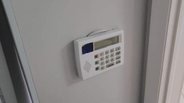 Finger pressing cancel button on home security alarm control panel