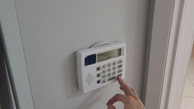 Close up of hand pressing numeric buttons on residential alarm keypad
