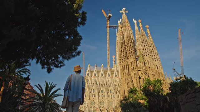 Female tourist near Sagrada Familia basilica in Barcelona during warm golden sunset light