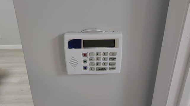 Close up video clip of a person pressing a colored function button on a residential home security alarm keypad mounted on a wall. Electronic access control and safety technology system indoors.