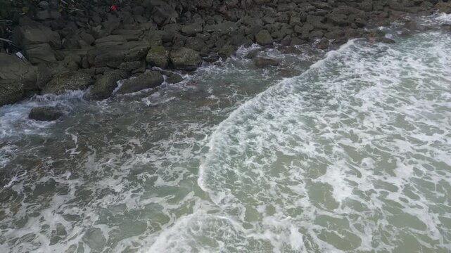 Waves churn the water into whitewash beside a rocky shoreline.
