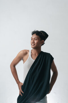 Young Smiling Asian Man in Traditional Cap and Draped Fabric Posing Confidently