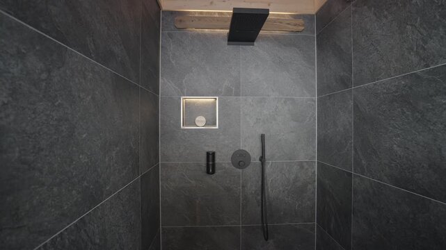 Stylish shower cubicle with black matte fixtures, slate tiles, and warm ambient lighting