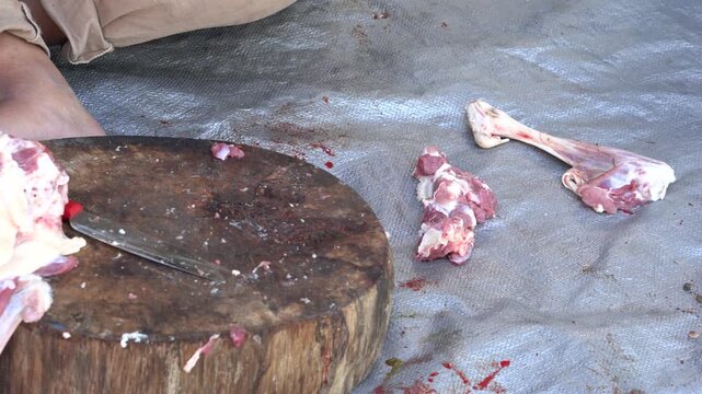 Raw meat being cut on a wooden board during eid aladha