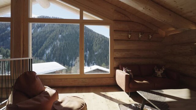 Bright sunbeam moving inside a cozy log cabin living room with a snowy mountain view
