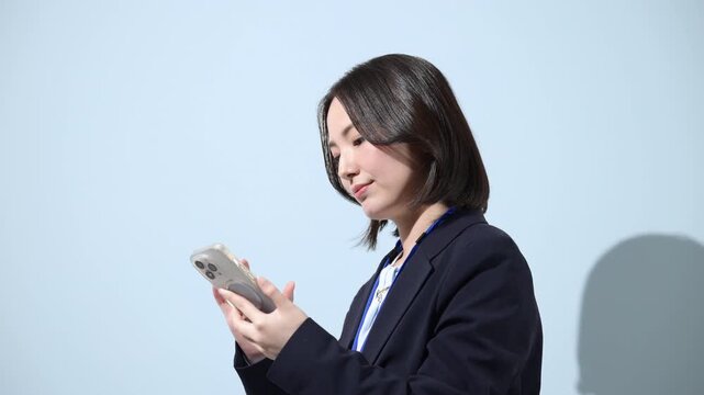水色背景でスマートフォンで検索、探す、問合せ、コンタクト等確認するビジネスウーマンの動画