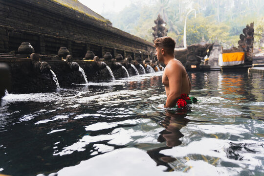 Young man in a balinese sacred temple water pool