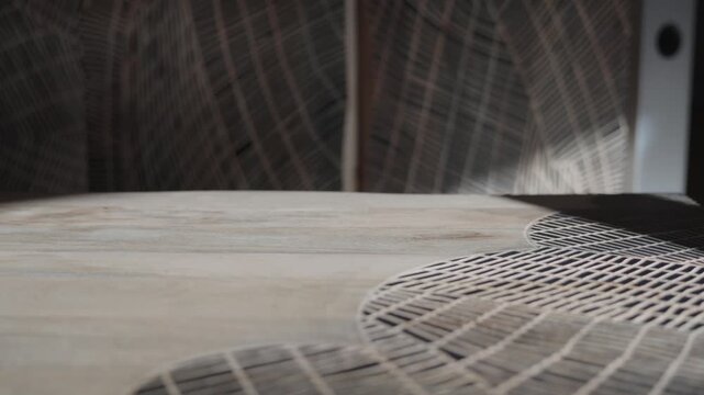 Detailed slow pan revealing a modern engraved geometric pattern on a light wood surface