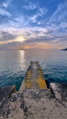 Obraz premium Dobra Voda pier on Adriatic coast at sunset with calm sea and moody sky