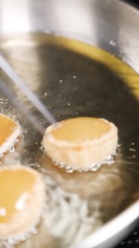 Chef friendo pani puri en sart&eacute;n de acero inoxidable (primer plano). Un chef profesional fr&iacute;e pani puri crujiente en una sart&eacute;n de acero. Comida callejera india, receta tradicional.