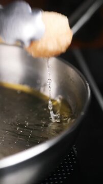 Chef friendo pani puri en sart&eacute;n de acero inoxidable (primer plano). Un chef profesional fr&iacute;e pani puri crujiente en una sart&eacute;n de acero. Comida callejera india, receta tradicional.