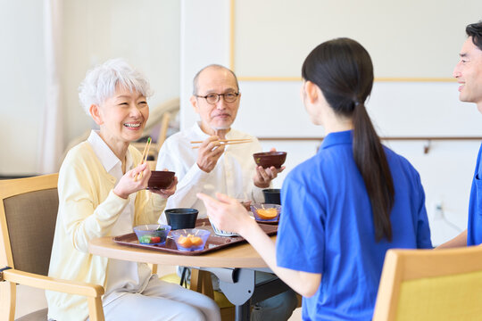 介護施設で話をしながら食事をするシニア