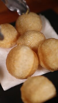 Chef presenta panipuri crujiente en una bandeja de pizarra negra. Un chef profesional muestra panipuri frito en una pizarra negra. Comida callejera india, presentaci&oacute;n elegante de la comida.